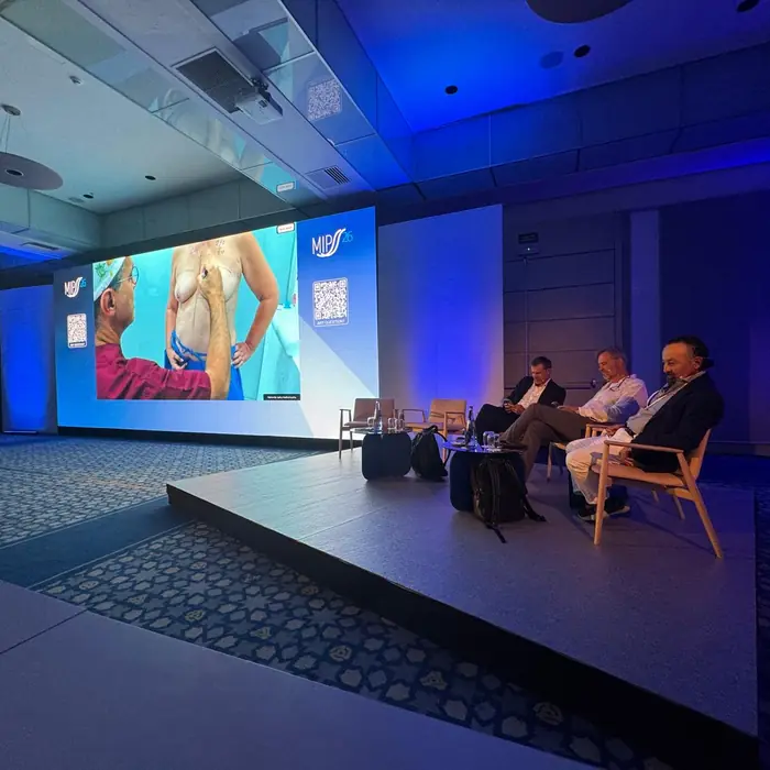 Live surgery broadcast on the main stage screen at MIPSS 2026